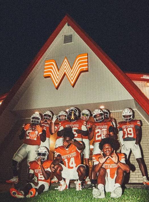 Full team stacked under the lit burger-stand sign at night
