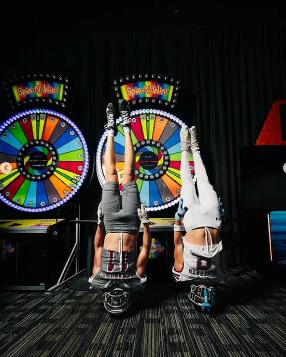 Handstands in front of neon prize wheels